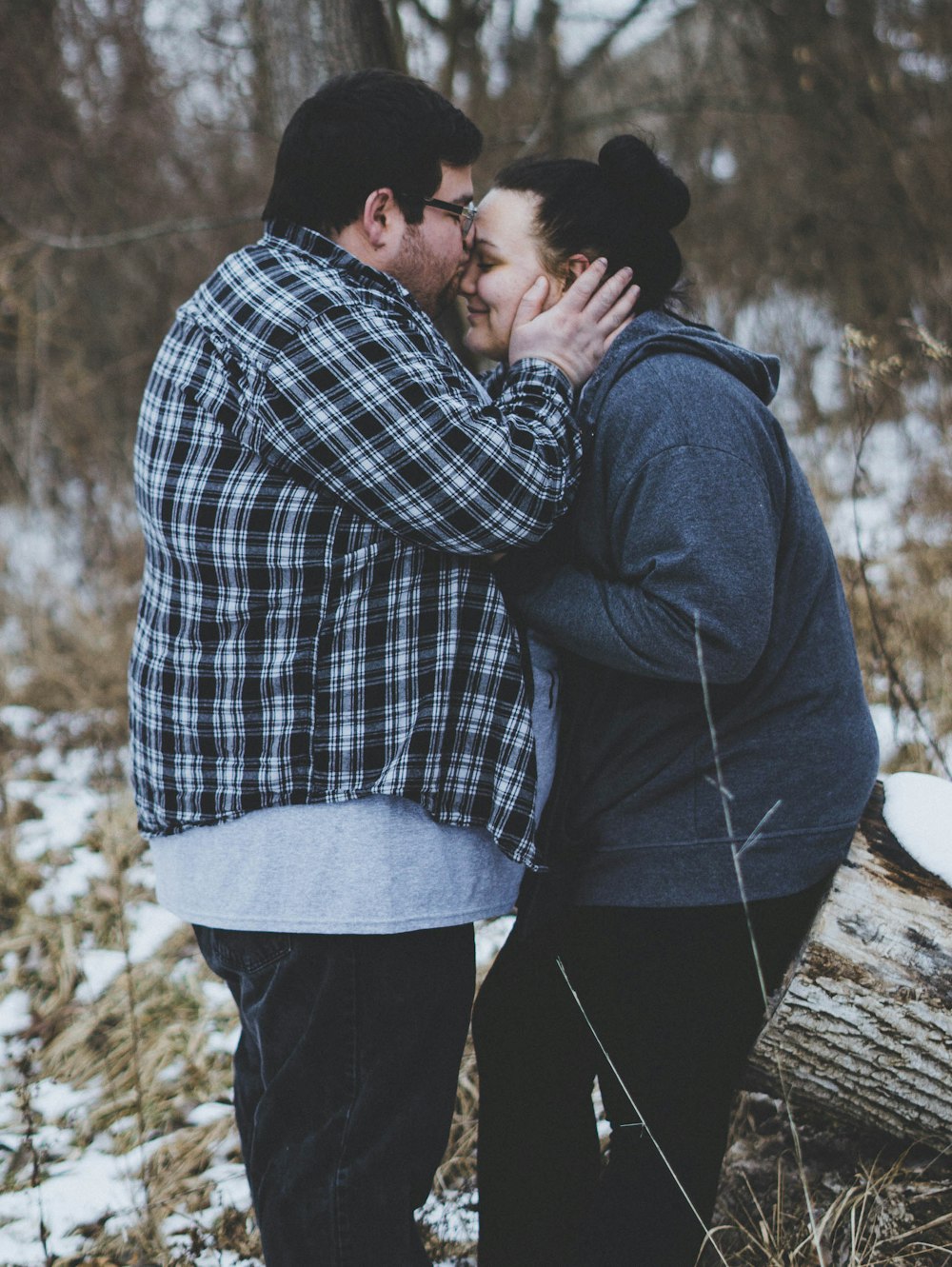 Mann küsst Frau, während er tagsüber in der Nähe von Bäumen steht