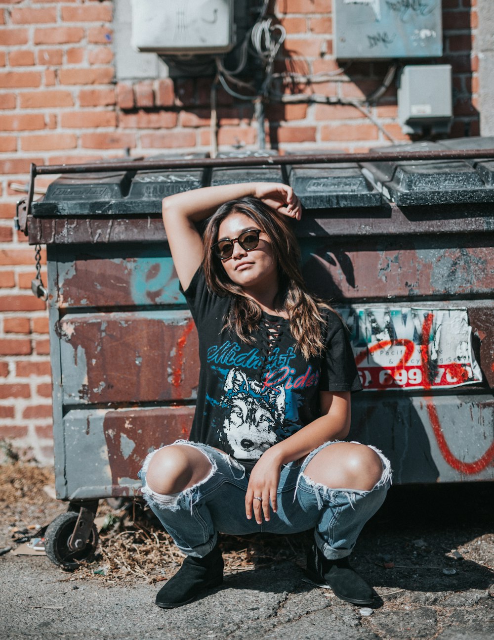 woman squatting beside trash bin