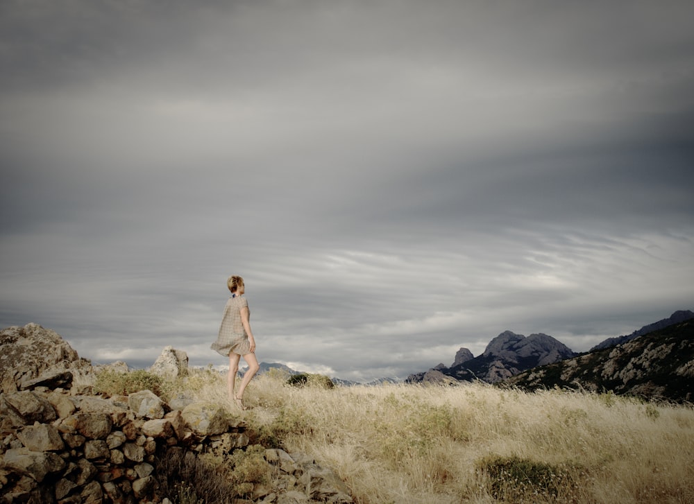 femme debout sur des rochers face à la montagne