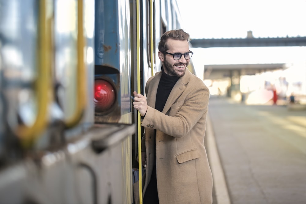 電車の脇に立つベージュのコートを着た男