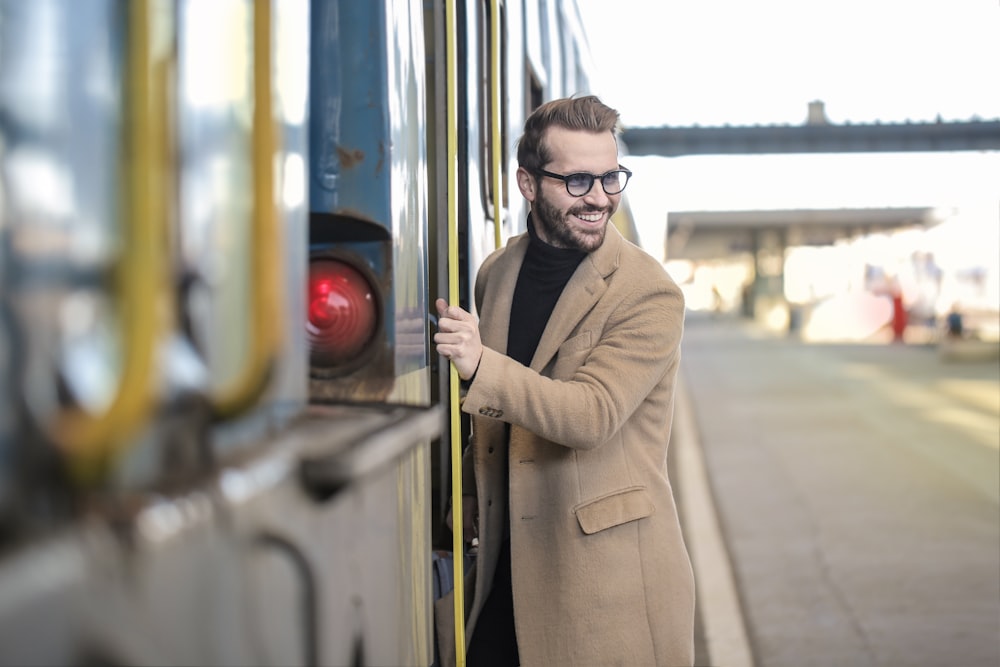 베이지색 코트를 입은 남자가 기차 옆에 서 있다