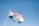 A flag with the words 'Sundays Are For Jesus' printed in large, bold letters. The flag has three horizontal stripes: orange, white, and blue. The flagpole is angled towards the left and is set against a clear blue sky, indicating a bright, sunny day.