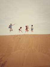 people jumping on sand