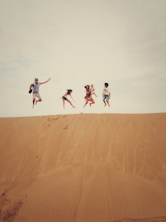 people jumping on sand