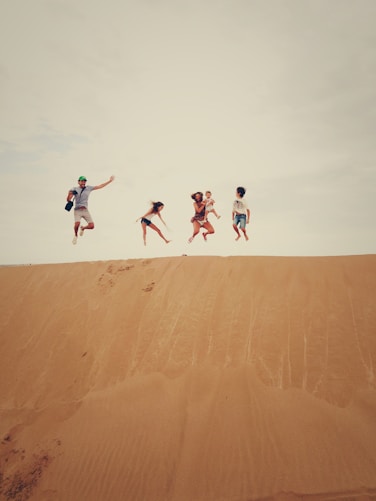 people jumping on sand