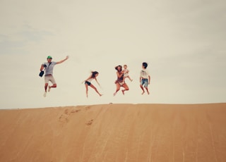 people jumping on sand