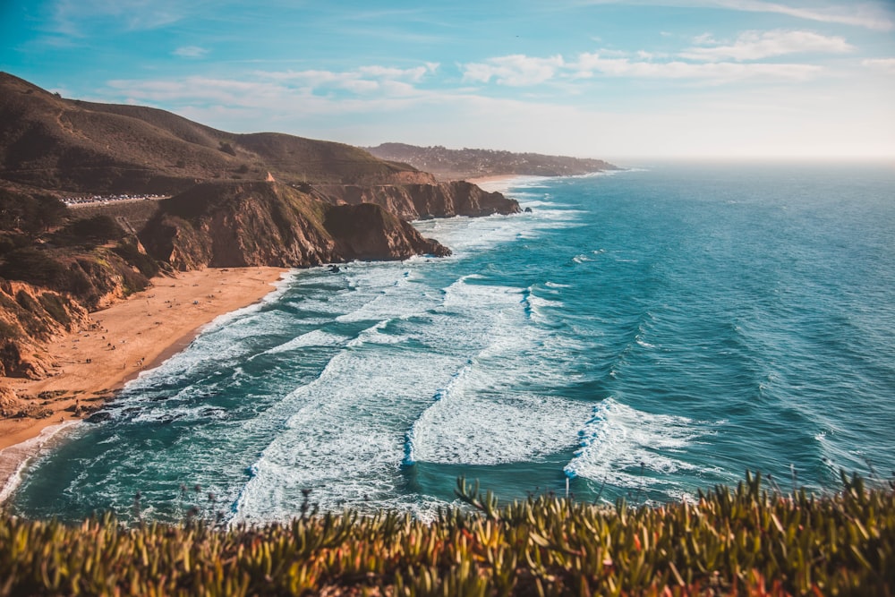 high-angle photo of sea waves rushing on shore