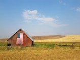 flag of United States of America hanged on brown house during daytime