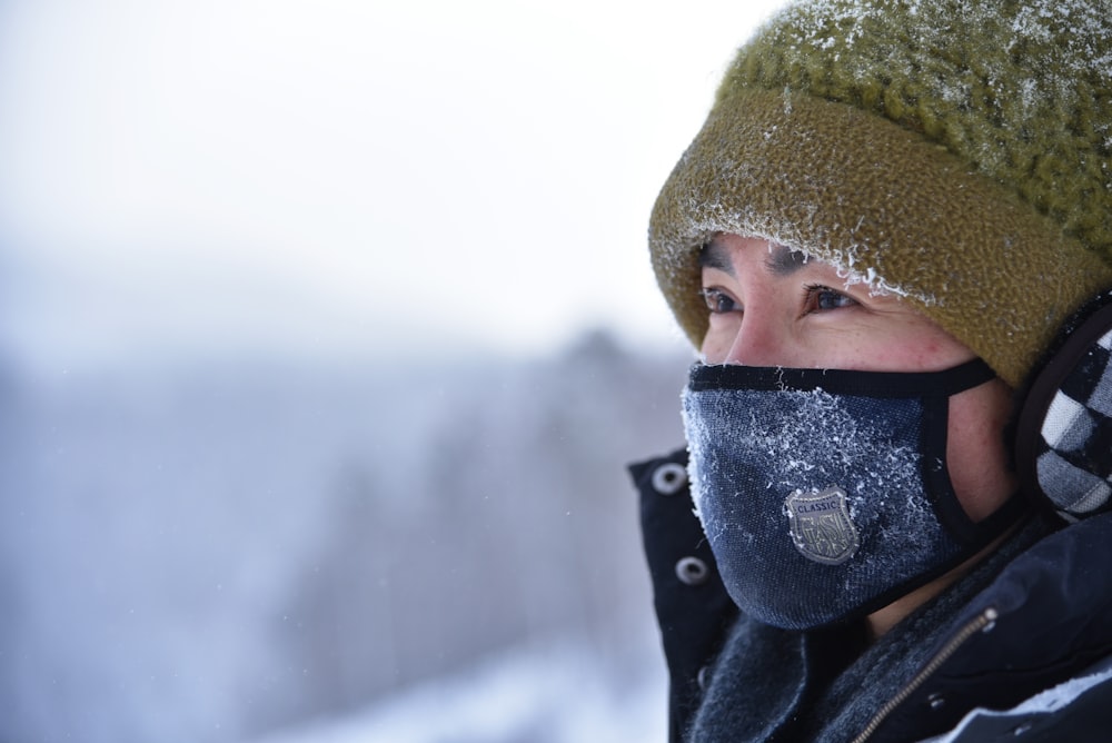 Femme portant un bonnet en tricot vert et un masque bleu