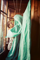 A smiling woman seller packaging vibrant textiles with care in a sunlit room.