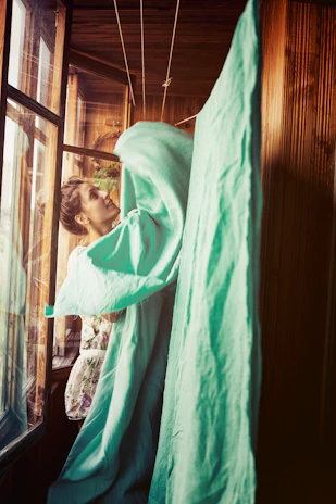 A cheerful person folding laundry with confidence in a cozy, sunlit room, highlighting daily chores embraced with pride.
