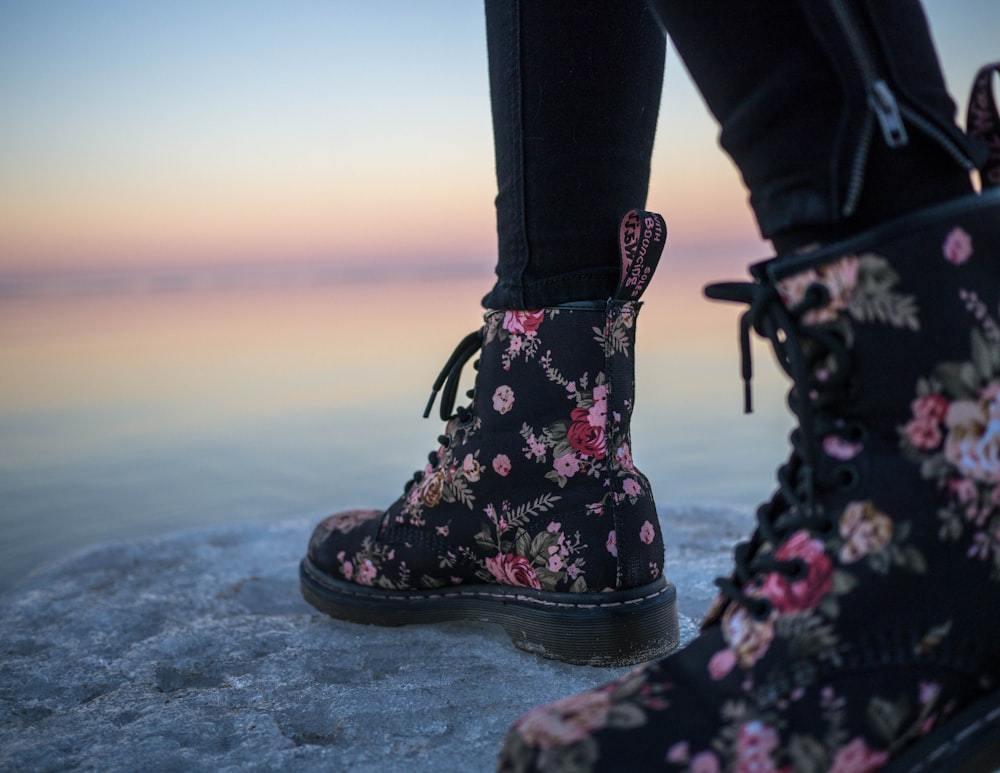 pessoa usando botas florais pretas e rosas