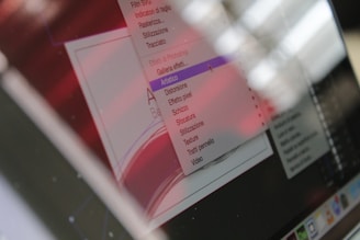 A computer screen displays a software interface with a dropdown menu in a language other than English, possibly Italian. The interface appears to be related to graphic design or image editing, with options like 'Artistico' and 'Texture' visible. The overall appearance is slightly blurred and has a red hue from reflections or lighting conditions.
