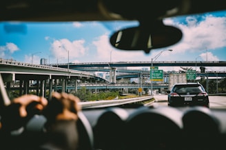 person sitting on vehicle near car and bridge at daytime