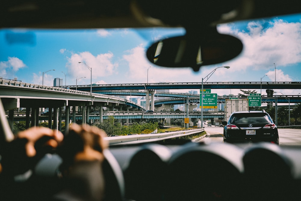 Persona sentada en el vehículo cerca del automóvil y el puente durante el día