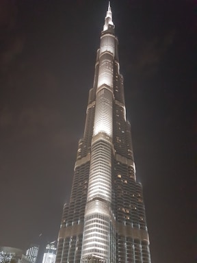 Elegant nighttime photo of a towering gold-lit luxury building with sharp architectural lines.
