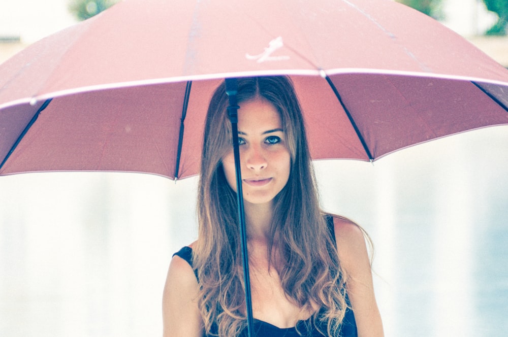 woman holding red umbrella in closeup photography