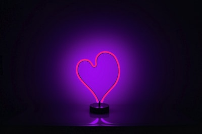 A vibrant contrast between cold machinery and a faintly glowing heart symbol in a darkened room.