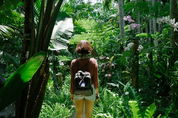 A happy traveler holding a map, standing on a lush tropical trail surrounded by vibrant flowers.