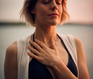 woman in white vest and black bikini with hand on chest