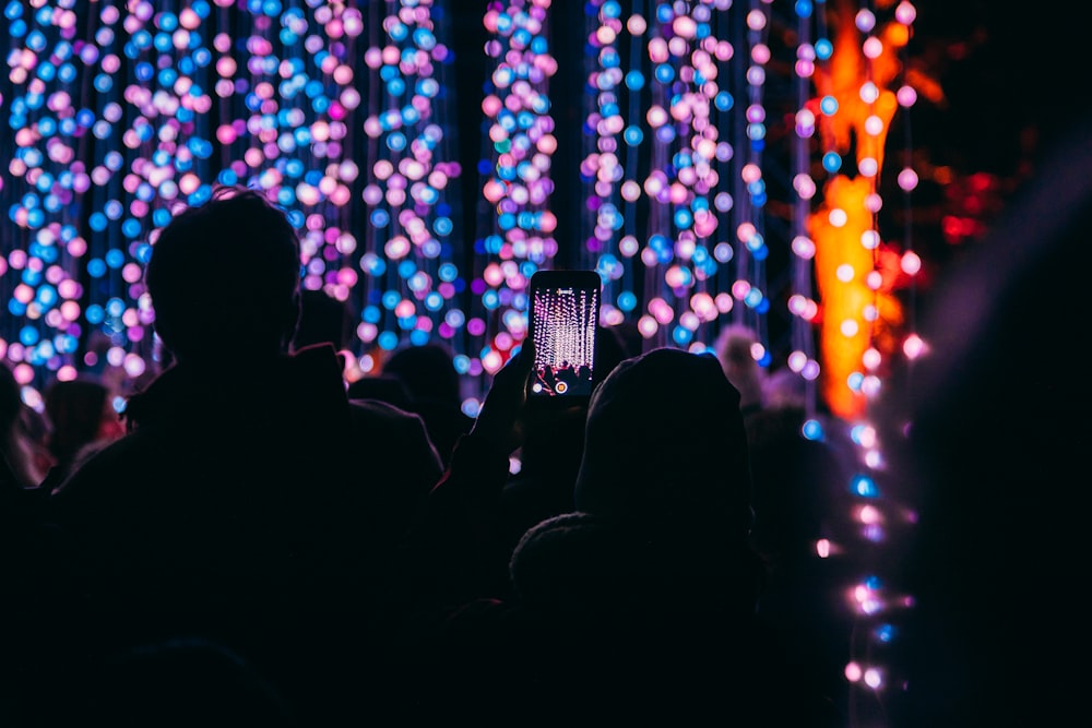 bokeh photography of person taking picture at stage