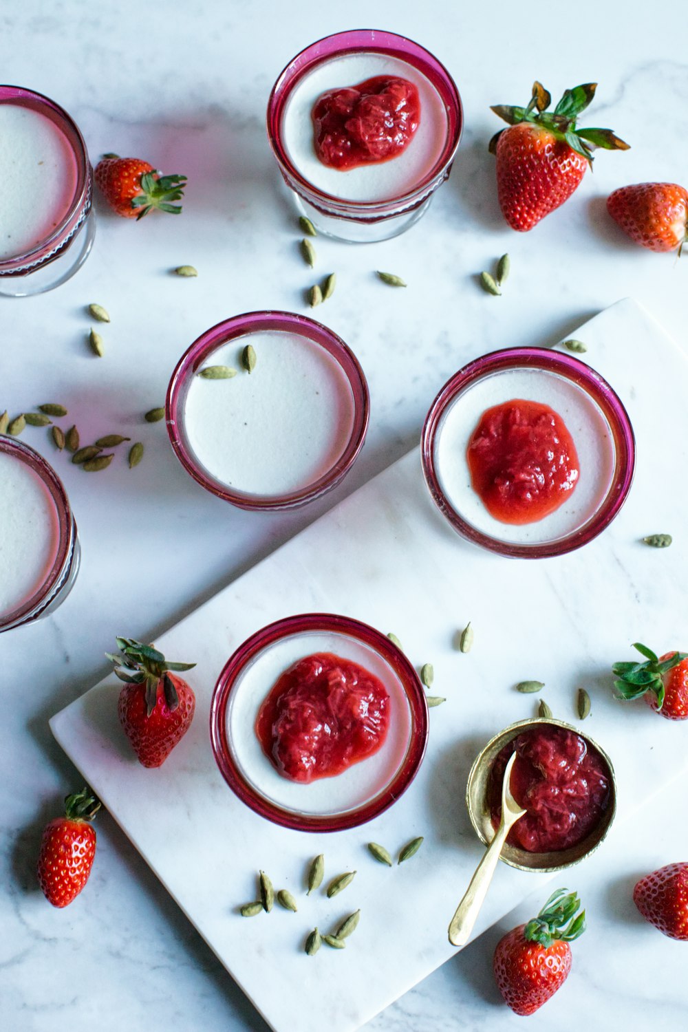 photo of clear glass filled with white liquid and strawberry toppings