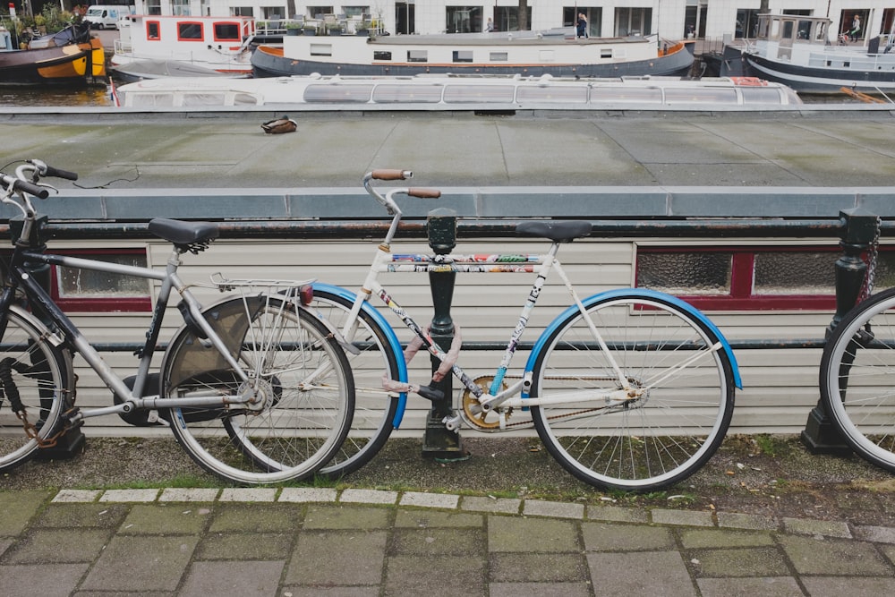 white and blue city bicycle leaning on black steel fence