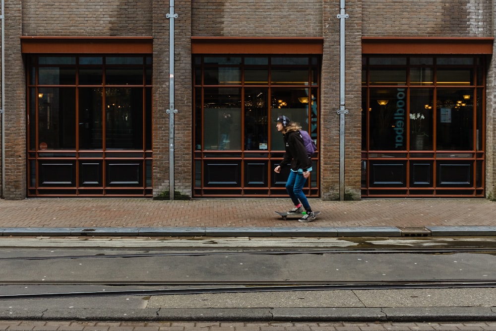 skateboard dell'uomo sul marciapiede marrone accanto all'edificio
