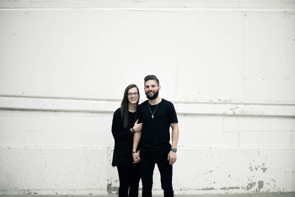 casal em pé na frente da parede de concreto branco