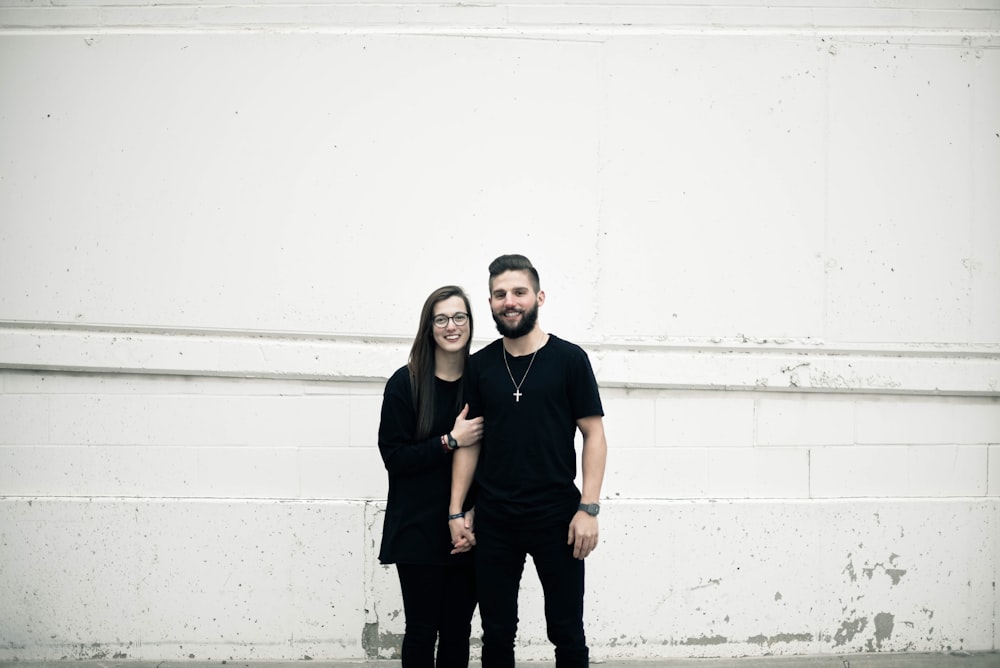 couple standing in front of white concrete wall