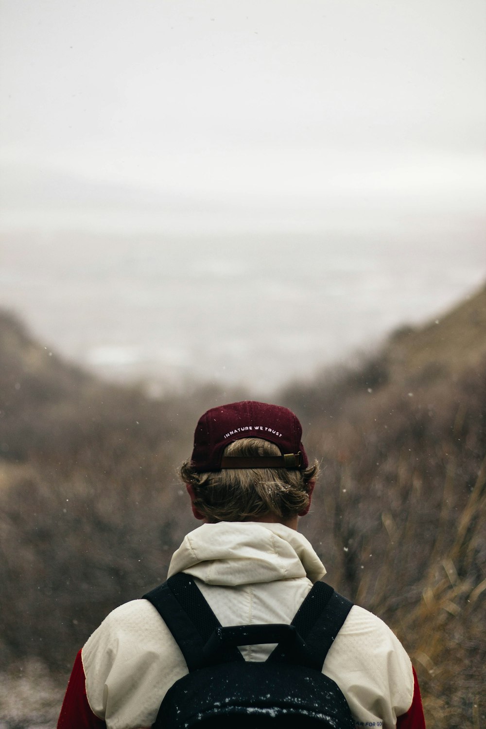 person wearing red cap and carrying black backpack