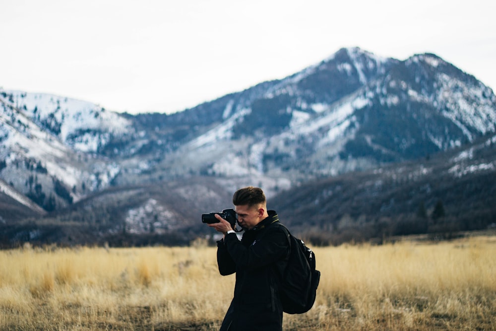 man taking photo on grass field at daytime