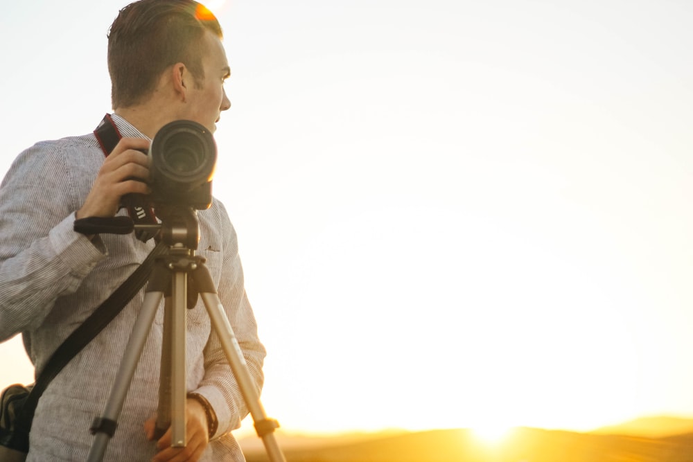 man holding DSLR camera during golden hour