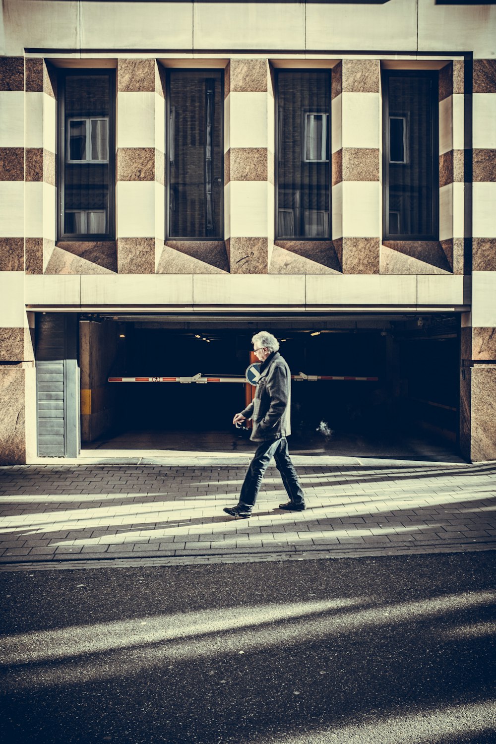콘크리트 구조물 앞에서 포장 도로를 걷는 남자