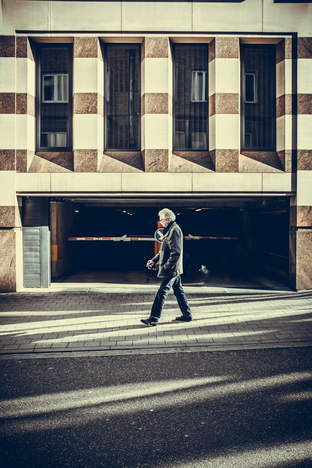 man walking on pavement in front of concrete structure