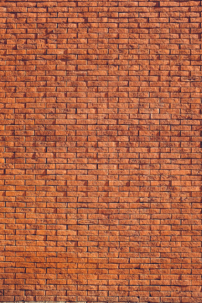 Weathered red brick wall laid in stretcher bond