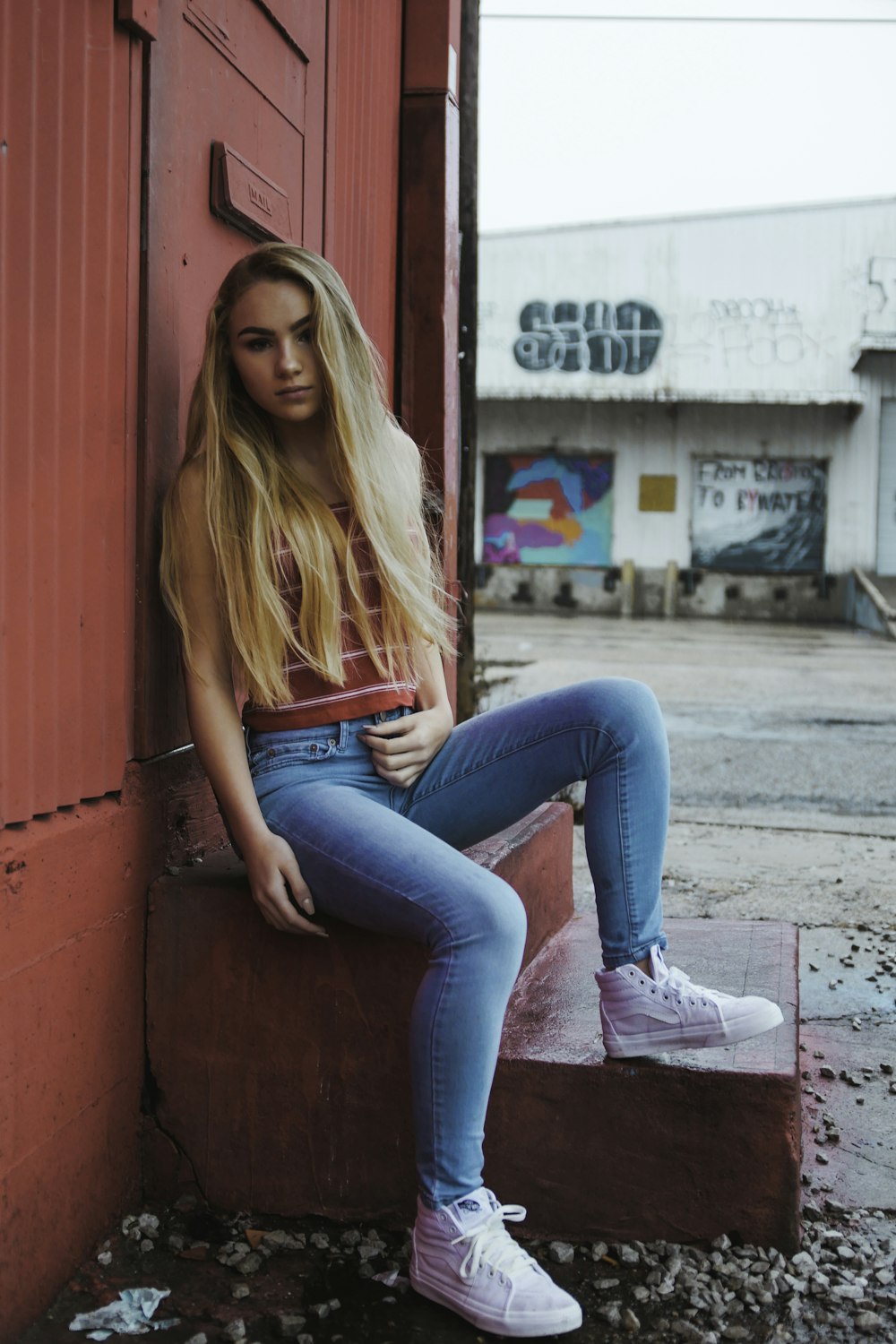 woman sitting on red stairs leaning on red door