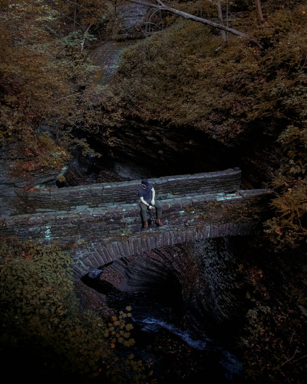 Mann sitzt auf grauer Betonbrücke