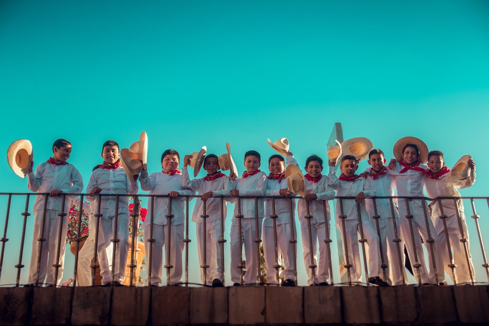 men standing on railings holding hats