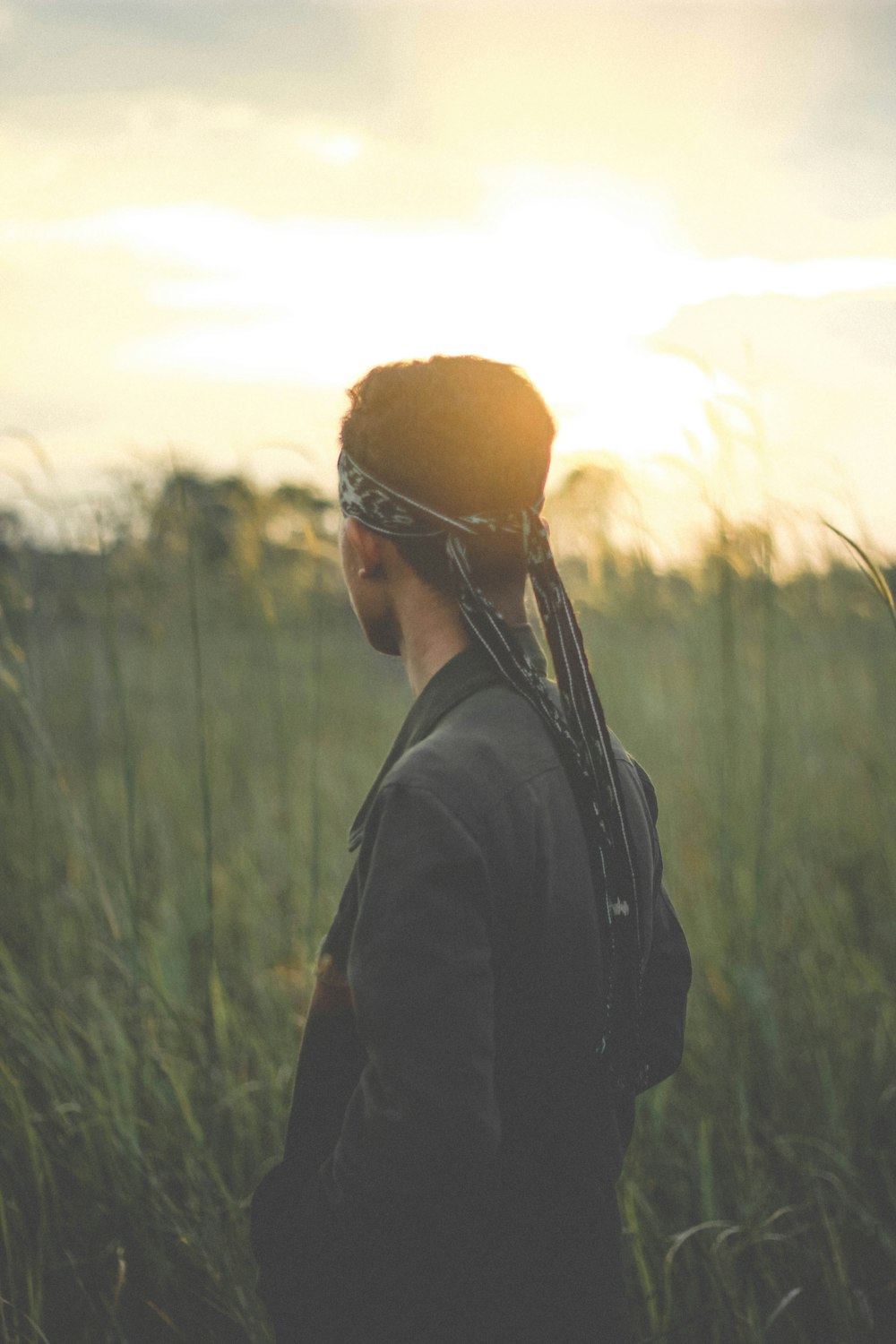 photography of man with bandana looking at grass