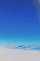 A serene mountain landscape under a clear blue sky with soft clouds.