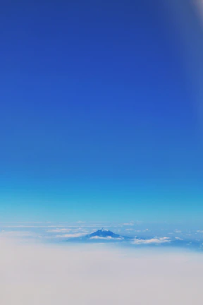 Serene mountain landscape under a clear blue sky with fluffy clouds.