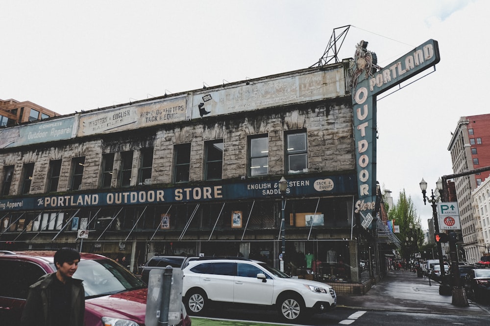 man walking on street beside vehicles and Portland Outdoor Store during daytime