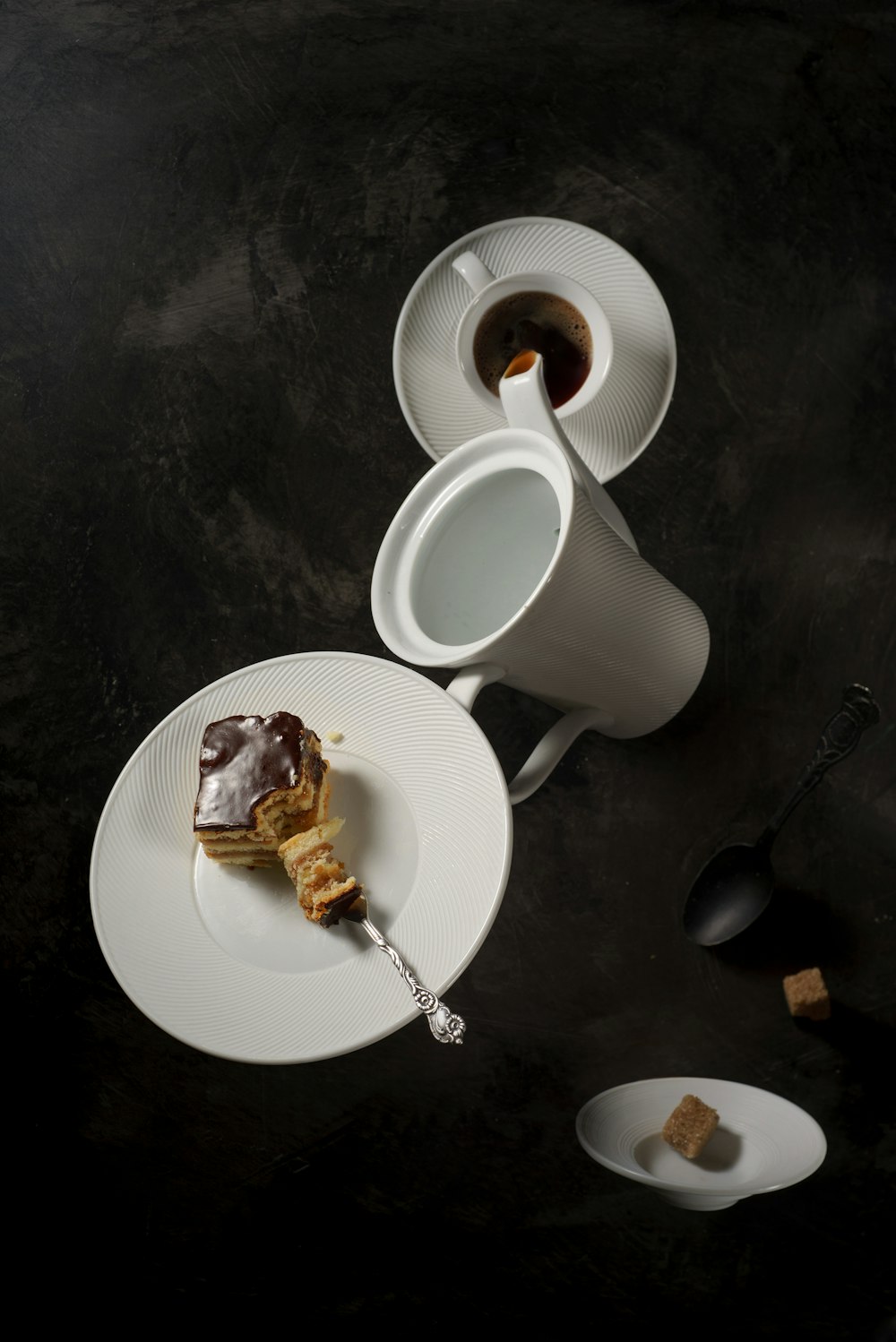 white ceramic pitcher pouring teacup with saucer