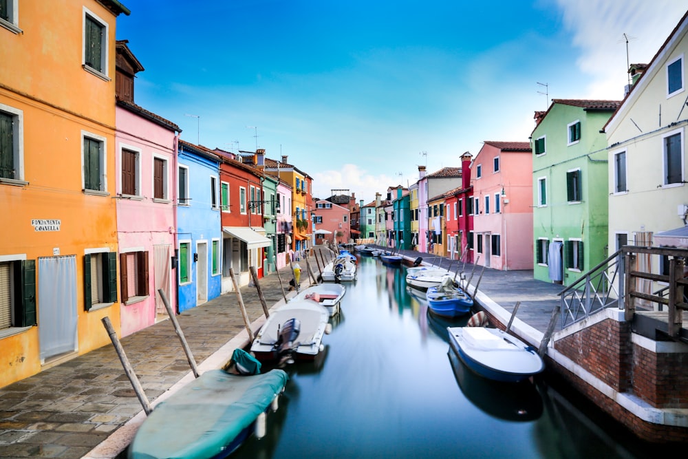 boats on canal between houses during daytime