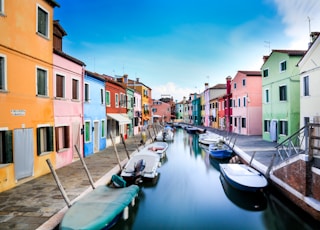 boats on canal between houses during daytime