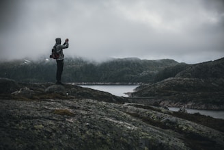 A moody shot of a model wearing moss green Mourne Peak jacket, standing against the rugged Mourne Mountains under heavy clouds.