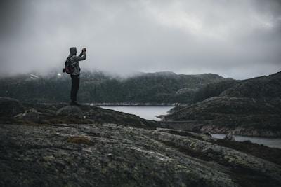A moody shot of a model wearing moss green Mourne Peak jacket, standing against the rugged Mourne Mountains under heavy clouds.