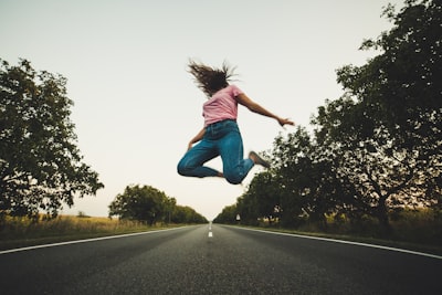 woman in pink top and blue pants jumps on road moldova teams background