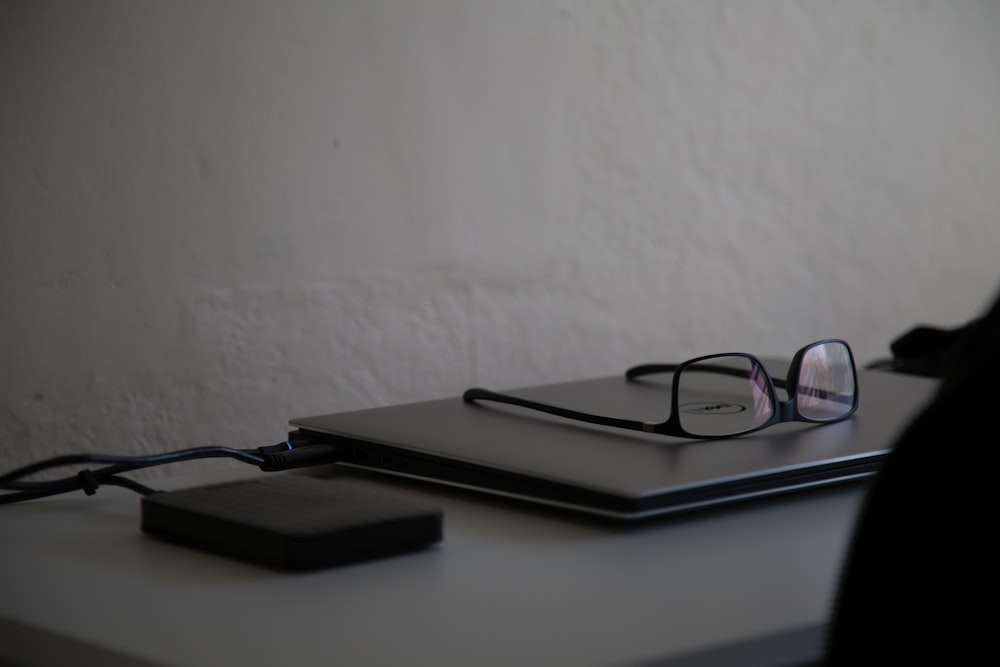 black framed eyeglasses on gray laptop computer near hard disc drive